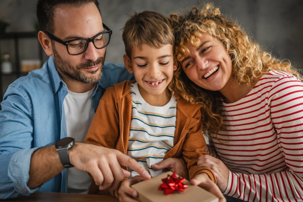 A family sits down to open a holiday present.